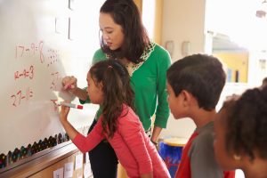 Pupil writing on the board at elementary school maths class